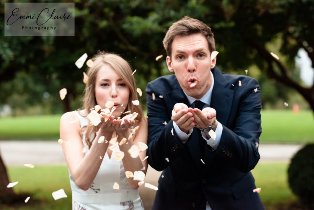 well-dressed couple has a little fun blowing confetti at the camera during a wedding celebration