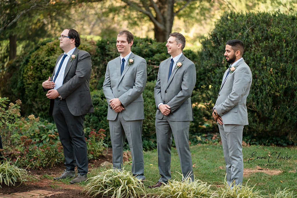 the groom standing outdoors with his groomsmen next to him as he awaits his bride to continue their wedding photography 