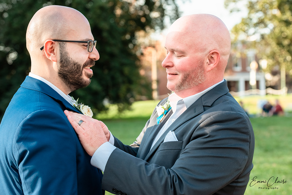 man in a grey suit straightens his new husband's tie during their unique COVID wedding day