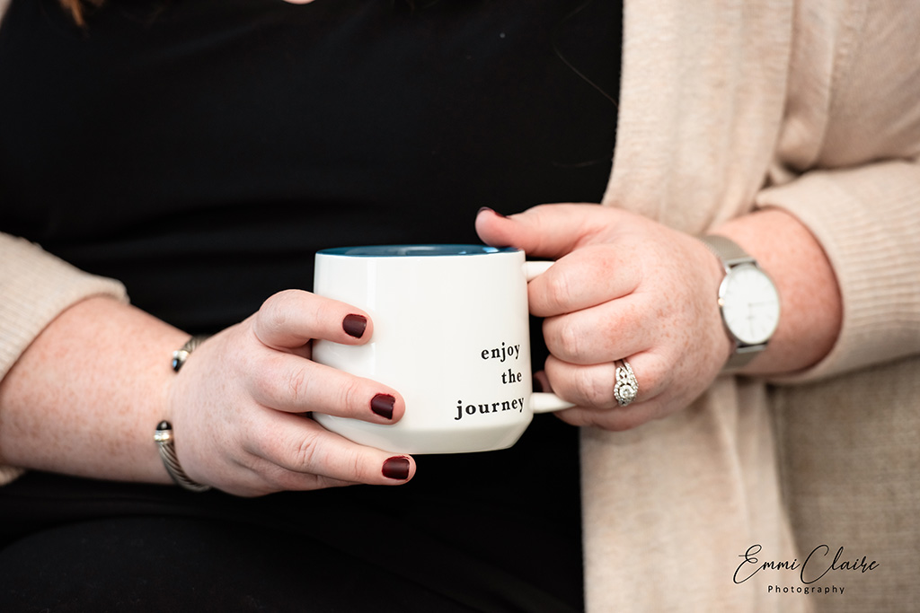 detail shot of hands holding a mug that says "enjoy the journey" during a branding photoshoot for psychotherapists 
