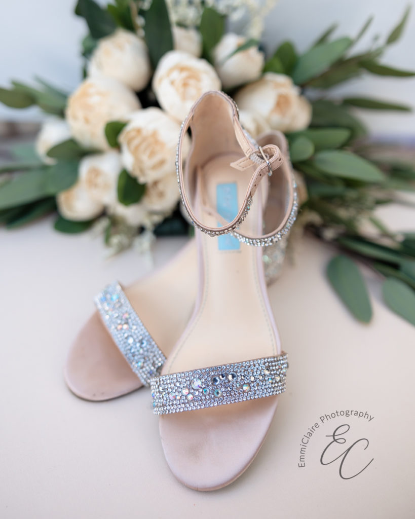 Detail shot of a southern bride's bedazzled wedding shoes with her cream bouquet set in the background behind them