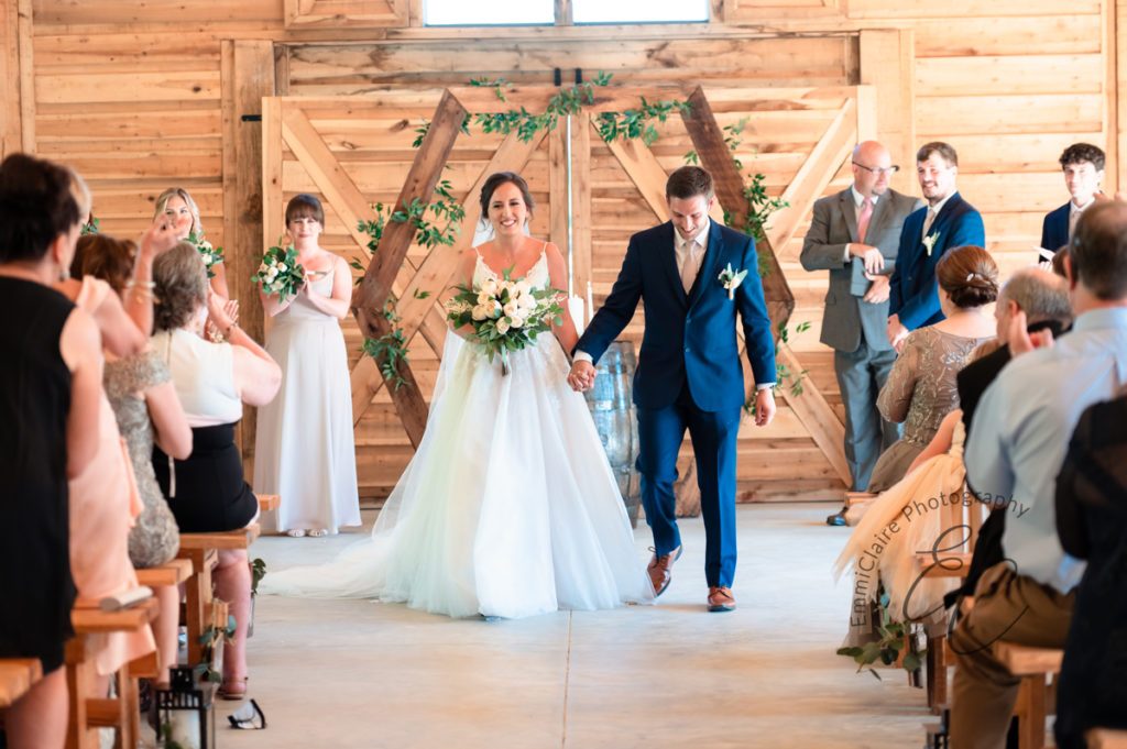 Bride and groom walking out of their ceremony together after saying I do as family and friends clap for them