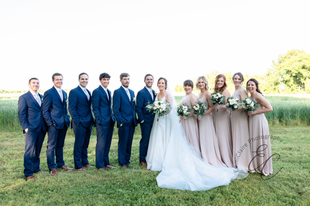Bride and groom pose together outside on the grass with their entire bridal party after their southern wedding ceremony