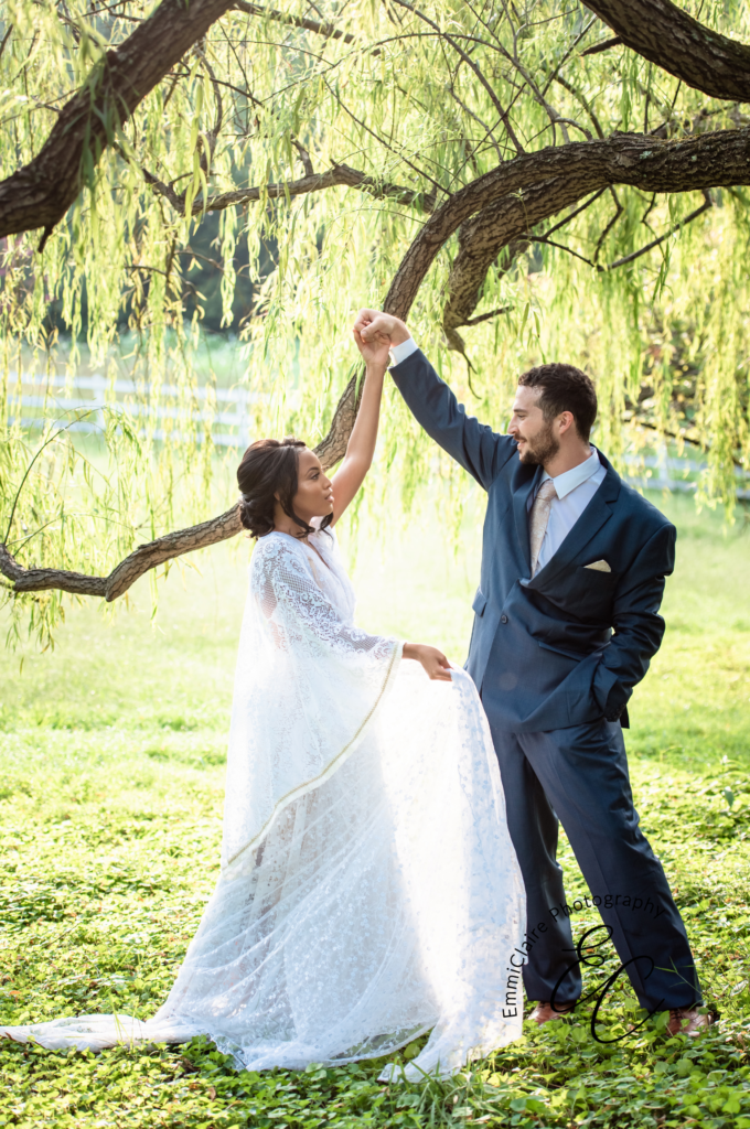groom twirls his beautiful bride in her lace dress underneath a tree as they celebrate documenting their big day with their dream wedding photographer