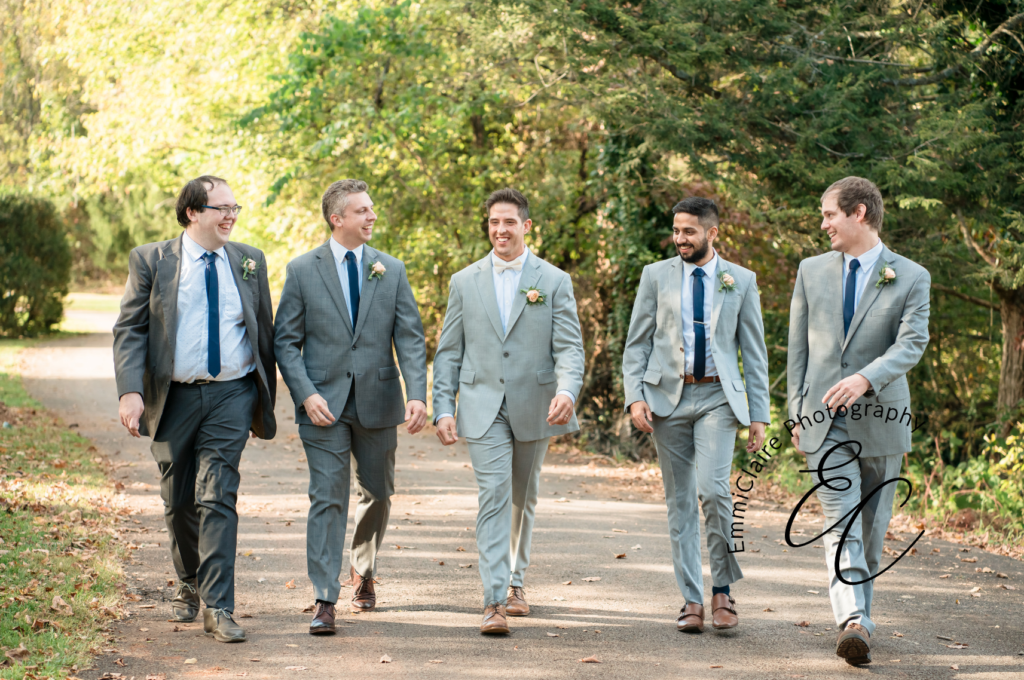 groom and groomsmen walking in a park surrounded by trees talking about how important it is to book your dream wedding photographer
