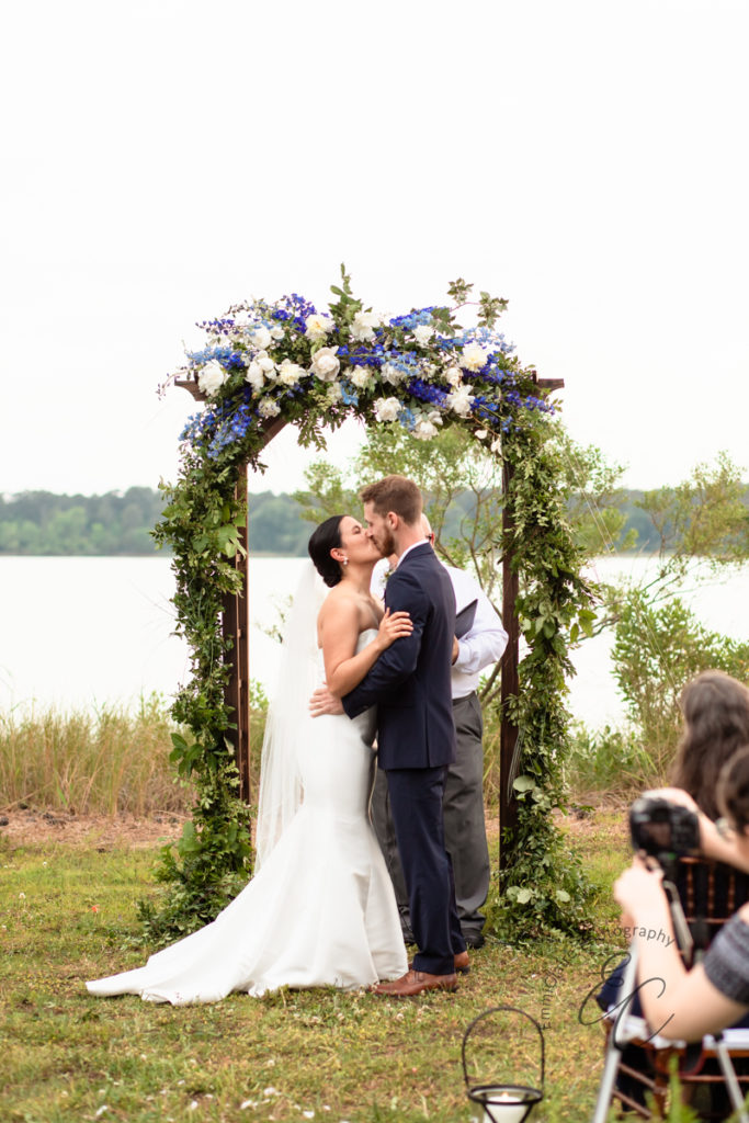 Bride and groom share a kiss to finalize their coastal outdoor wedding ceremony among close family and friends