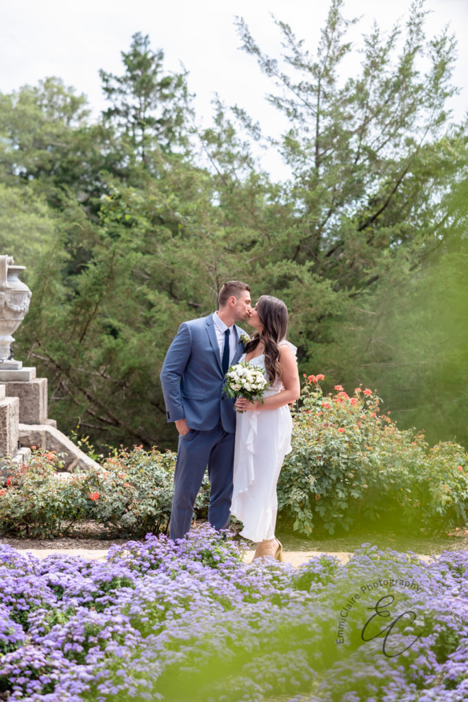 Newlywed couple shares a kiss in an outdoor garden following their small courthouse wedding