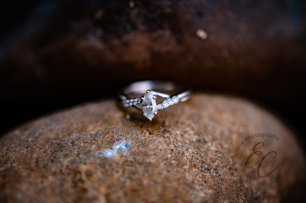 detail shot of a sparkling diamond engagement ring sitting on a rock captured during an engagement photoshoot