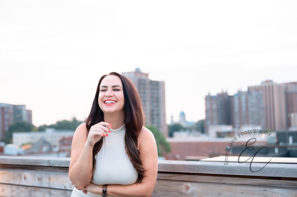 matchmaker laughs with personality and confidence on a rooftop in a white outfit 