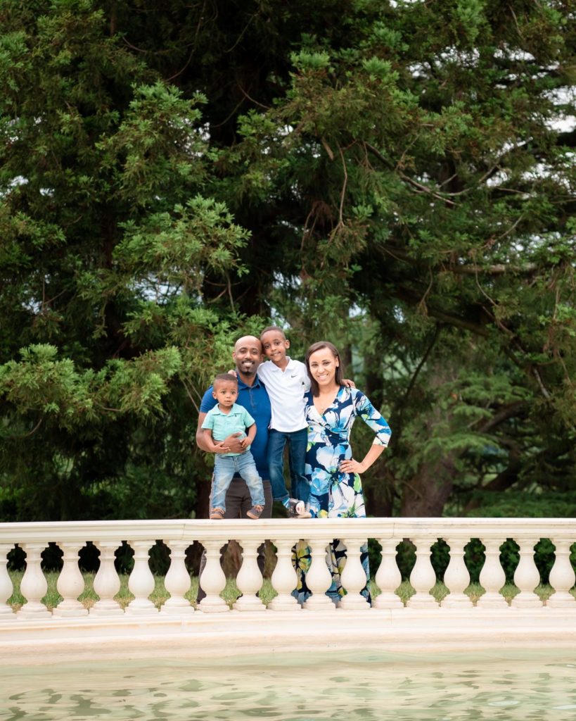 family of four, including mom, dad, and two young boys coordinate in white and blue for their outdoor family photoshoot