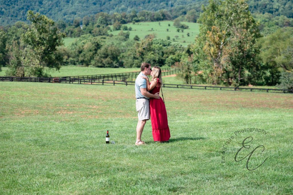 newly engaged couple kiss in a beautiful green space surrounded by horses and nature during their proposal photoshoot
