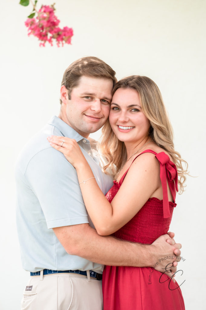 portrait of a newly engaged couple standing closely with the sides of their heads touching as they smile towards the camera
