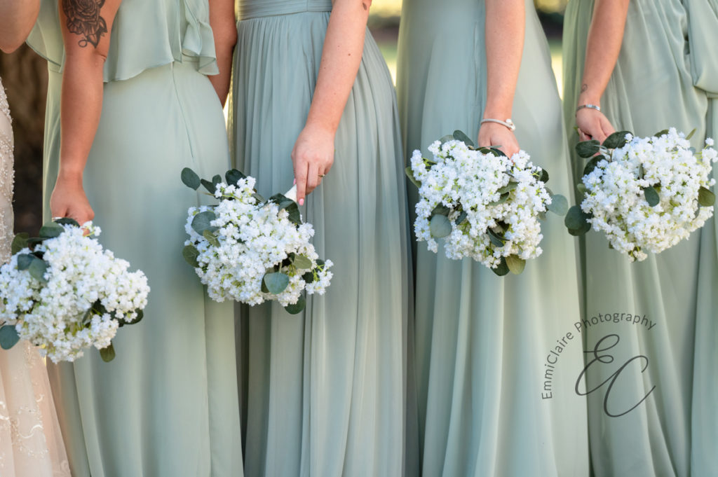 detail shot of the bridesmaid's bouquets as they stand together side by side in long, sea foam green bridesmaids dresses.