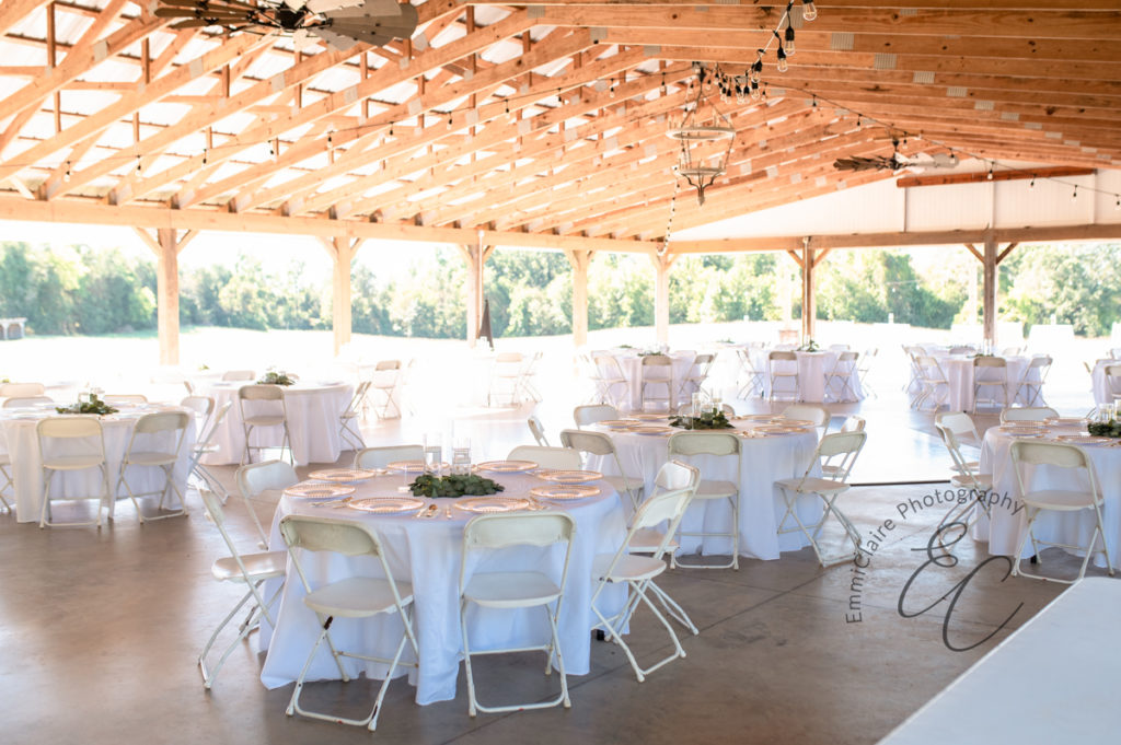 Pastoral wedding reception venue photographed empty before the guests have arrived with beam ceilings and white tables