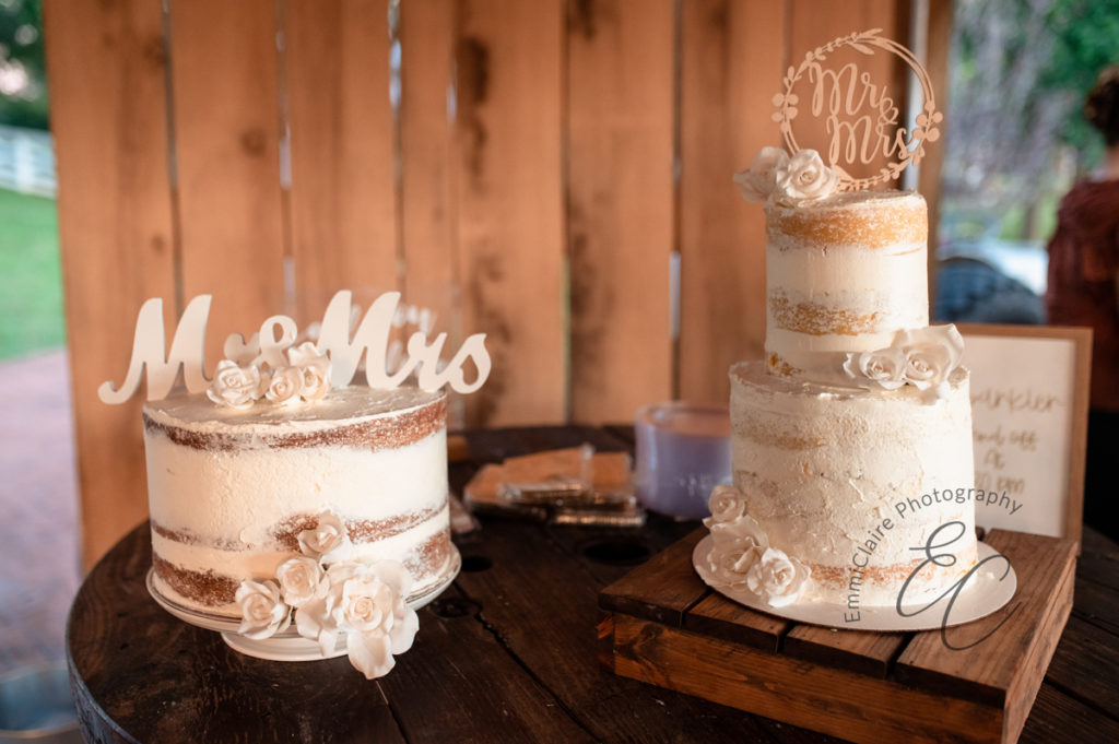 A one tier and a two tier white-iced wedding cake photographed side-by-side at the bride and groom's wedding reception with the words "Mr and Mrs" on top of each