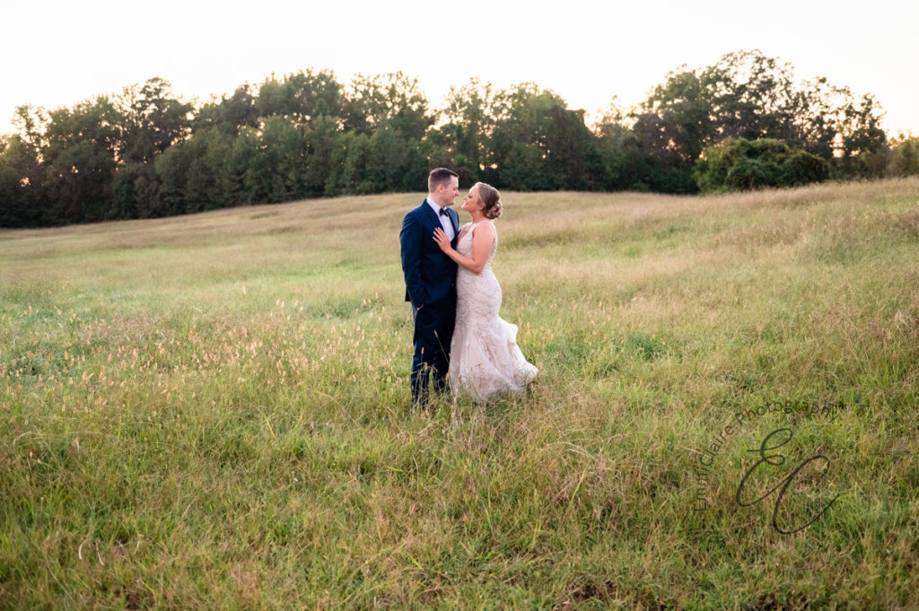 bride and groom lock eyes in a grassy field enjoying a quiet moment together before joining their guests at their wedding reception