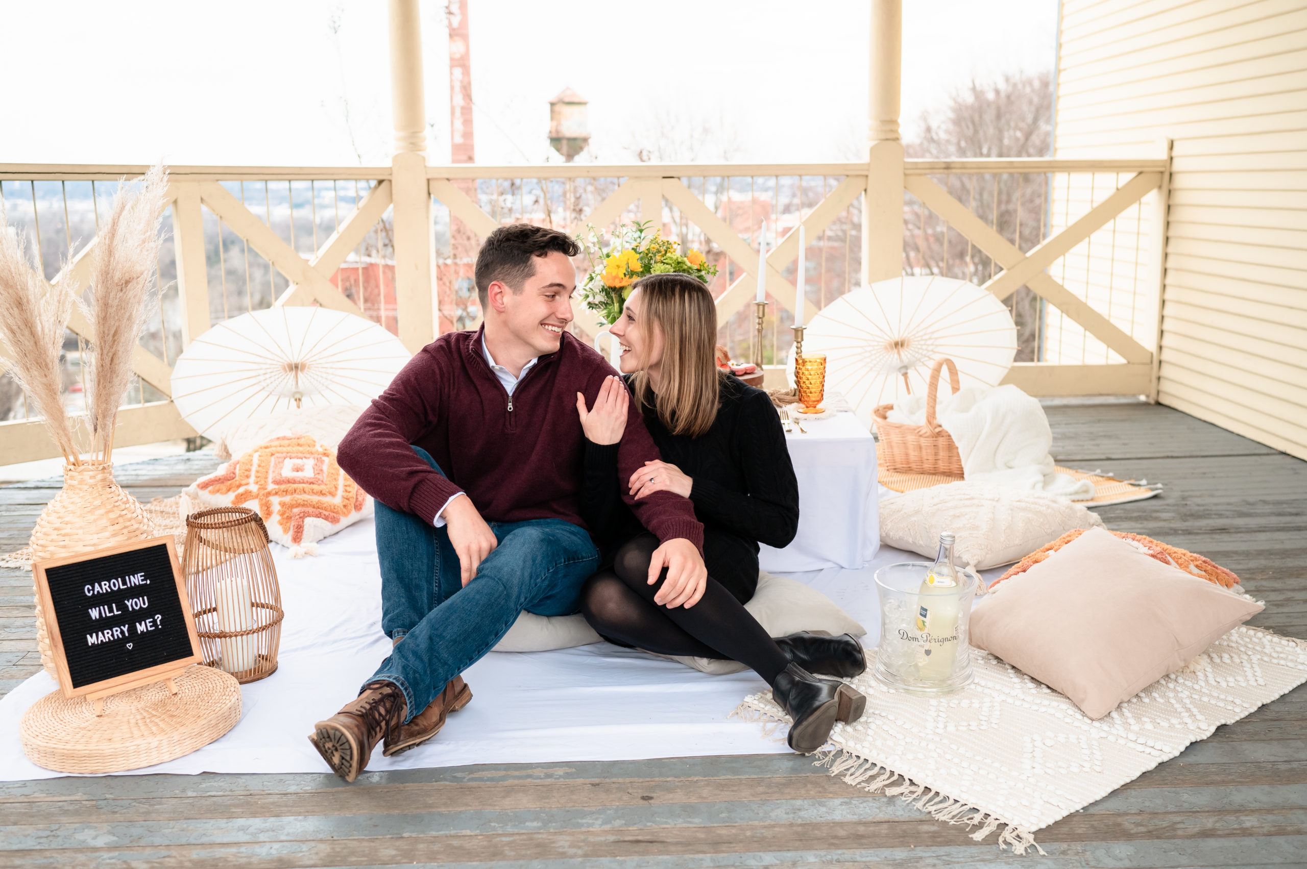 Justin and Caroline sit cuddled up under the gazebo immediately following their proposal at Libby Hill. Behind them, a luxury picnic experience. by RVA Picnics They gaze smilingly at one another.