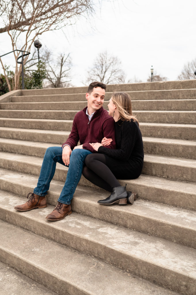 Justin and Caroline gazee lovingly at each other while they sit on a stairway at Libby Hill Park.