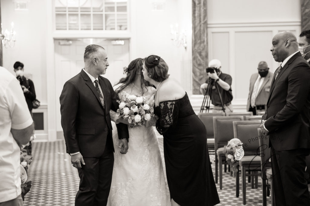 The bride's mother leans in to give her a kiss halfway down the aisle at Pope Chapel.