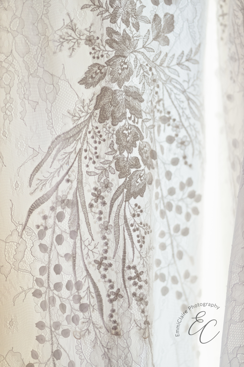 A close up view of the floral and leaf-patterned lace on the bride's gown.