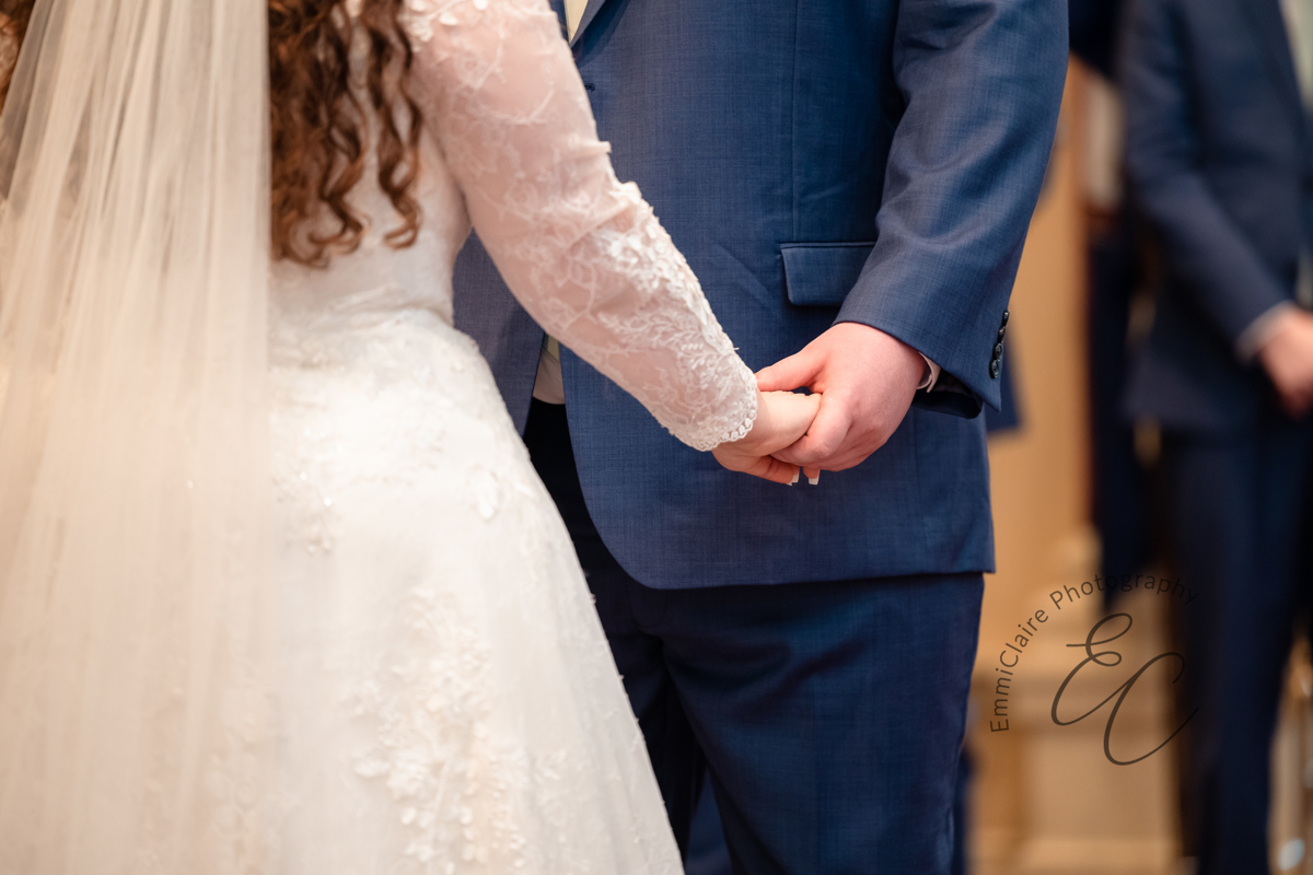 The couple holds hands during their wedding ceremony at Pope Chapel at Christopher Newport University.