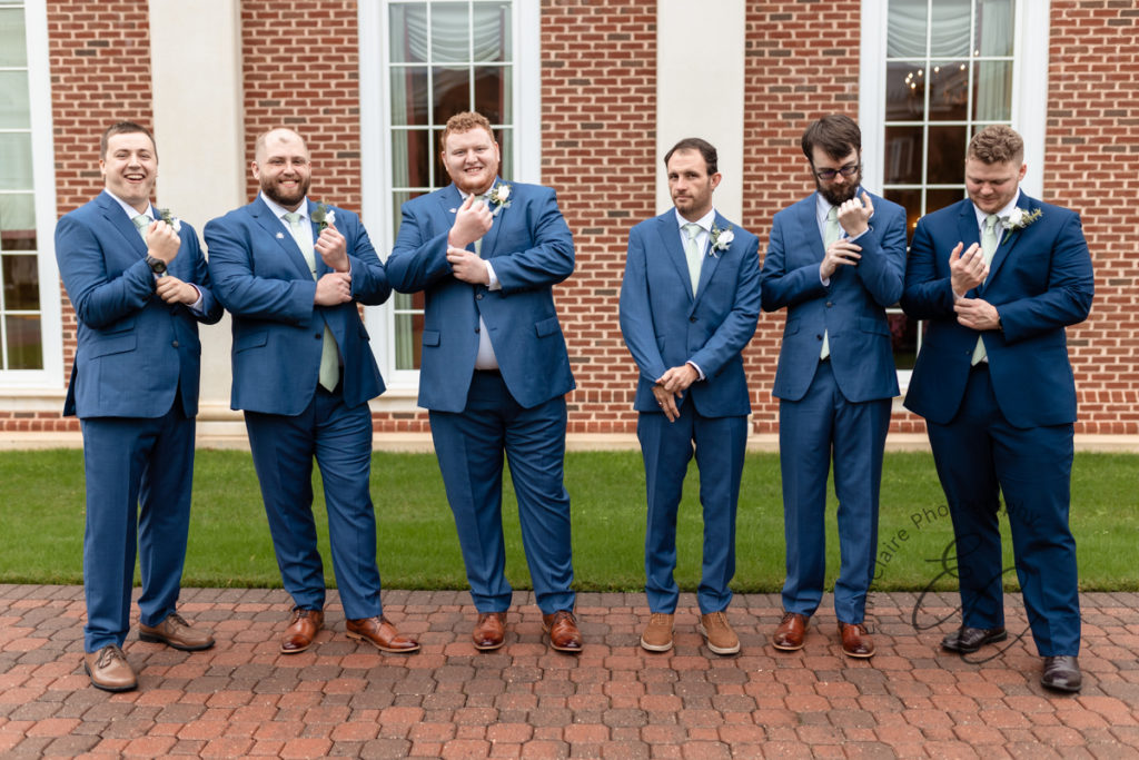 The groom and his groomsmen all adjust their cufflinks.