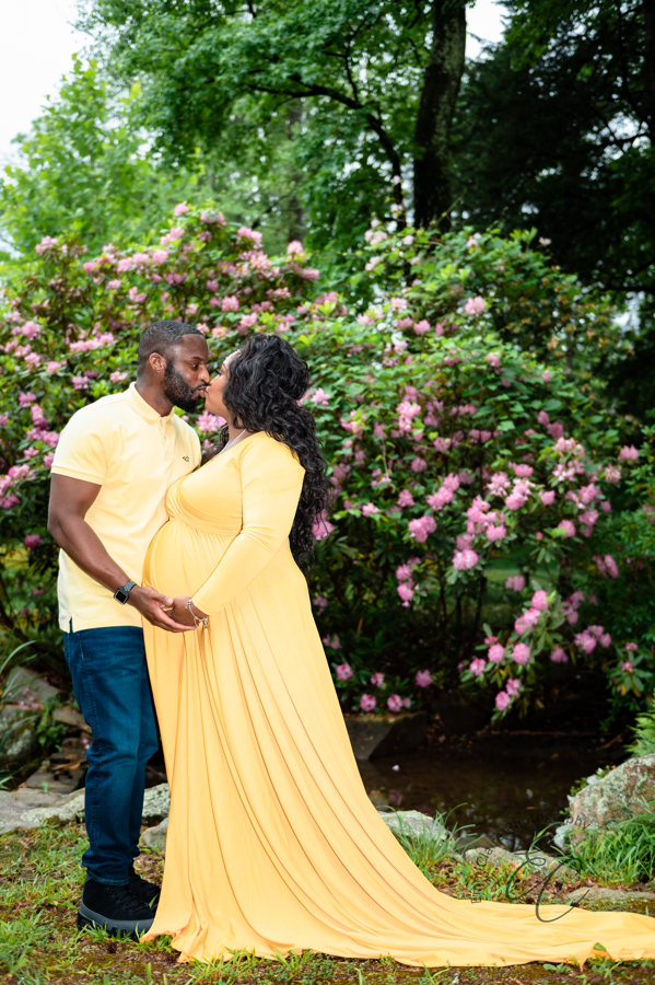 Shana and Chris kiss in front of a beautiful azalea bush at Maymont Park during their maternity session in Richmond, VA.