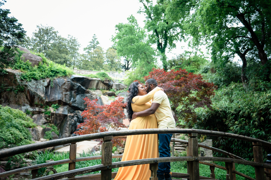 Shana and Chris kiss on the Japanese Bridge at Maymont Park, a waterfall in the background.