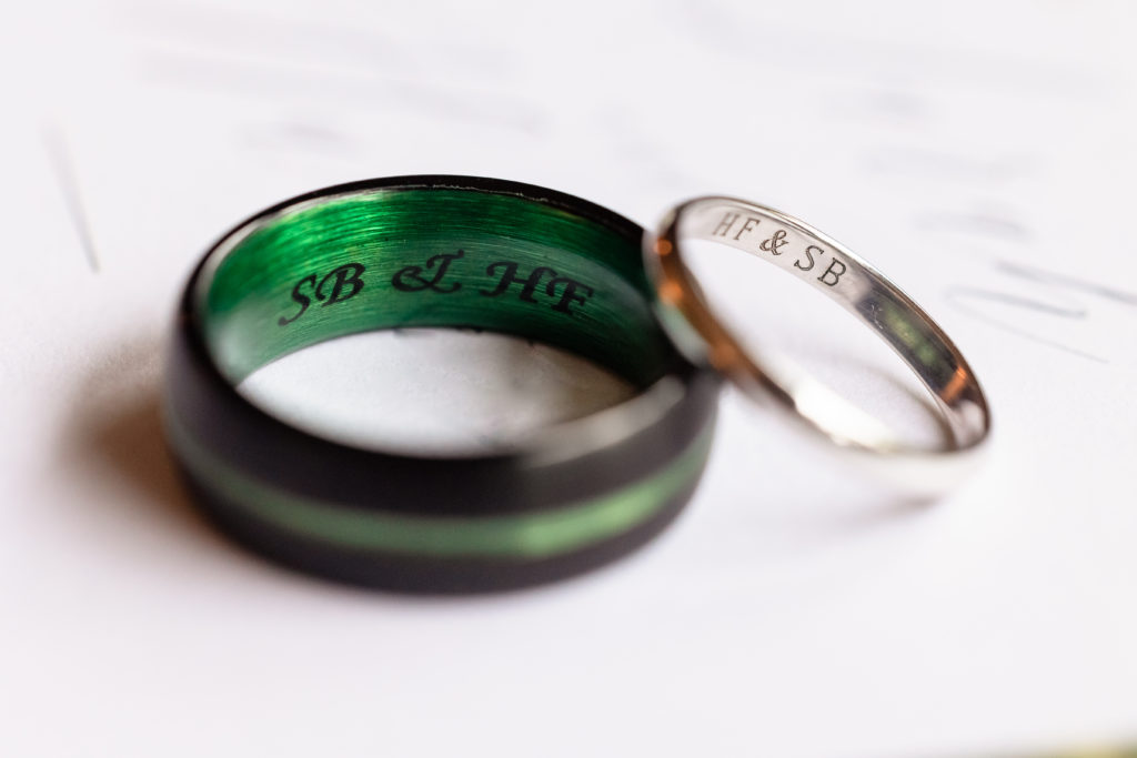 Close up shot of bride and groom's wedding bands, both engraved on the inside with the couple's initials.