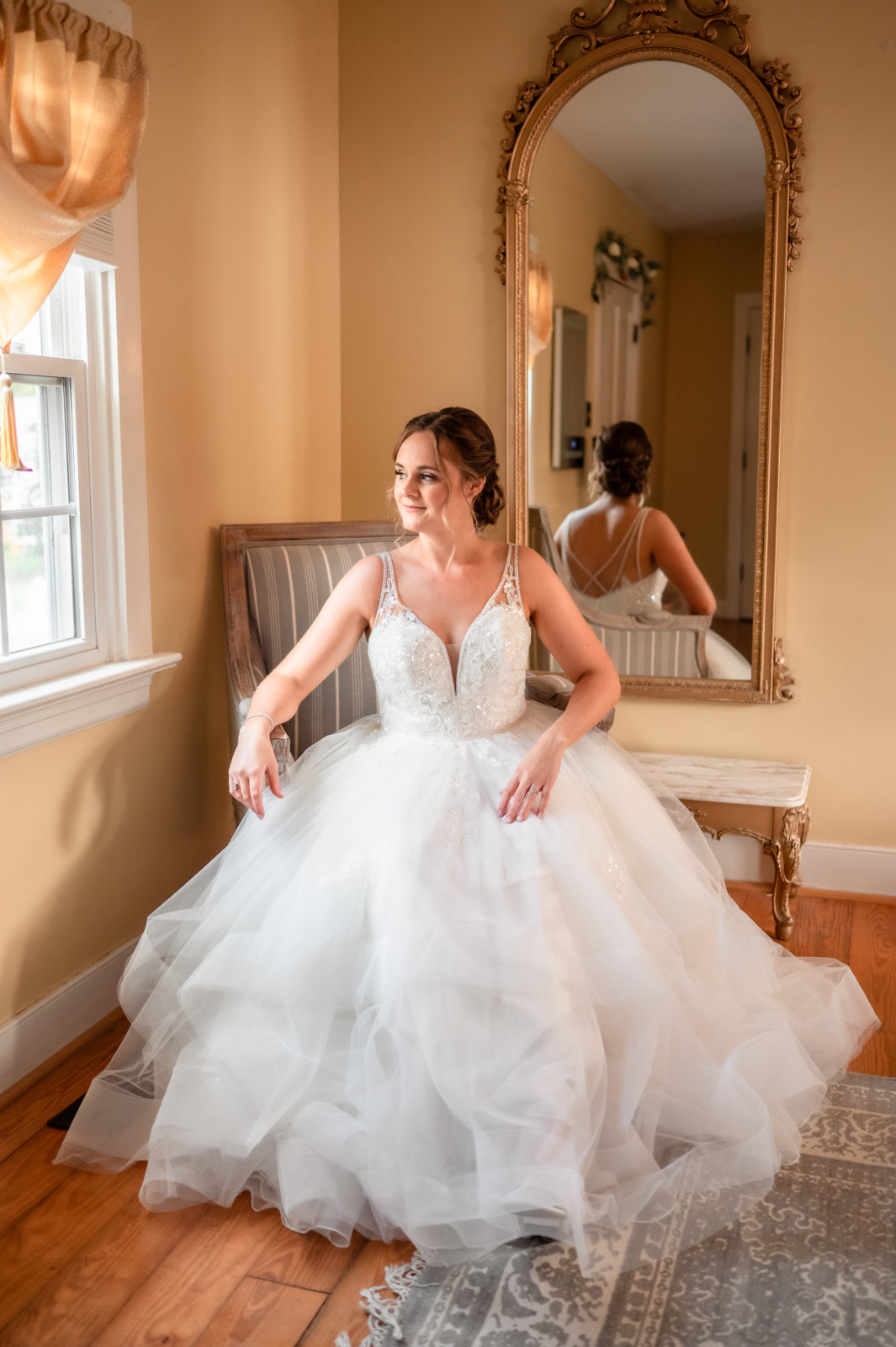 A hot of Lynne's beautiful wedding gown with her sitting on chair