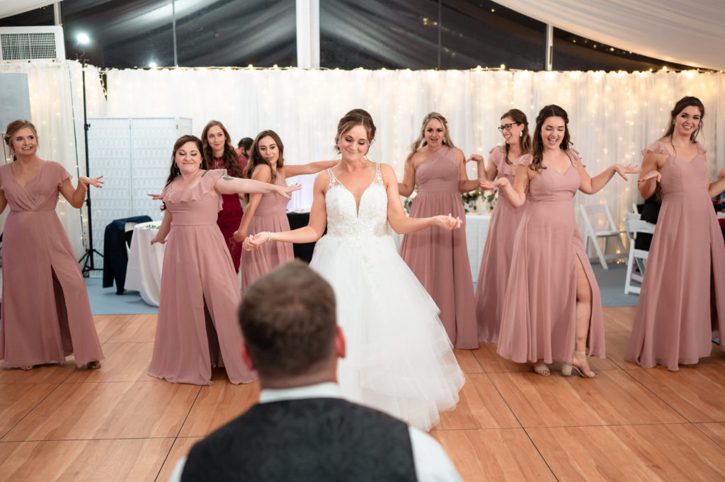 Bride and her bridesmaids dancing for the groom at their wedding