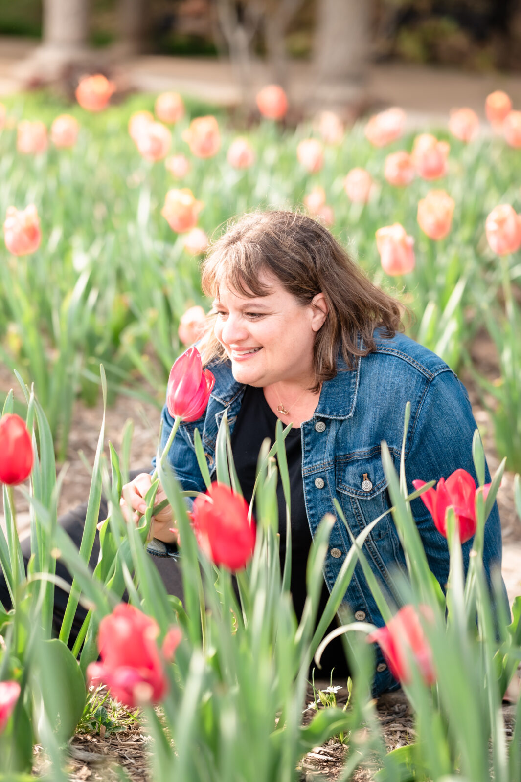 woman sitting down smelling tulips