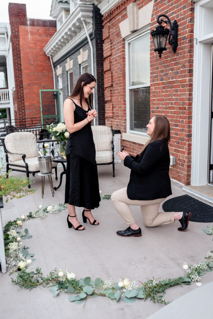 woman proposing at sunset with photographer capturing the moment