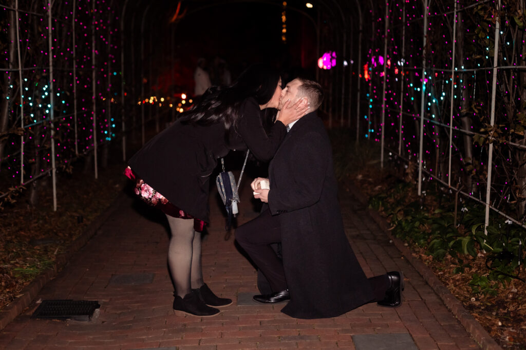 Kevin proposing to Terri at Lewis Ginter GardenFest of Lights, surrounded by sparkling holiday lights, captured by EmmiClaire Photography.