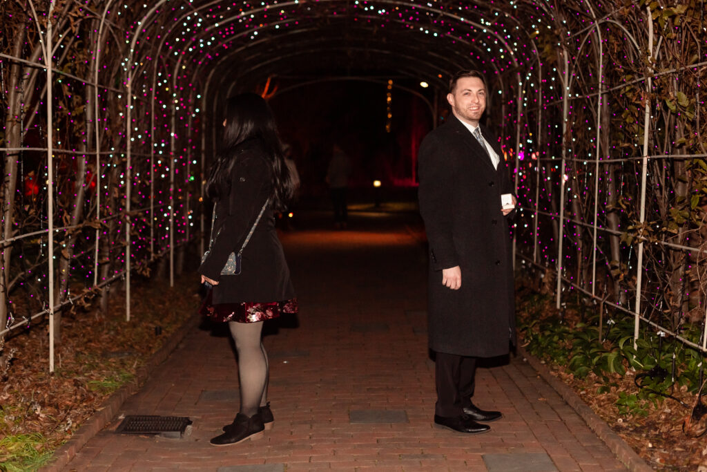 Kevin proposing to Terri at Lewis Ginter GardenFest of Lights, surrounded by sparkling holiday lights, captured by EmmiClaire Photography.