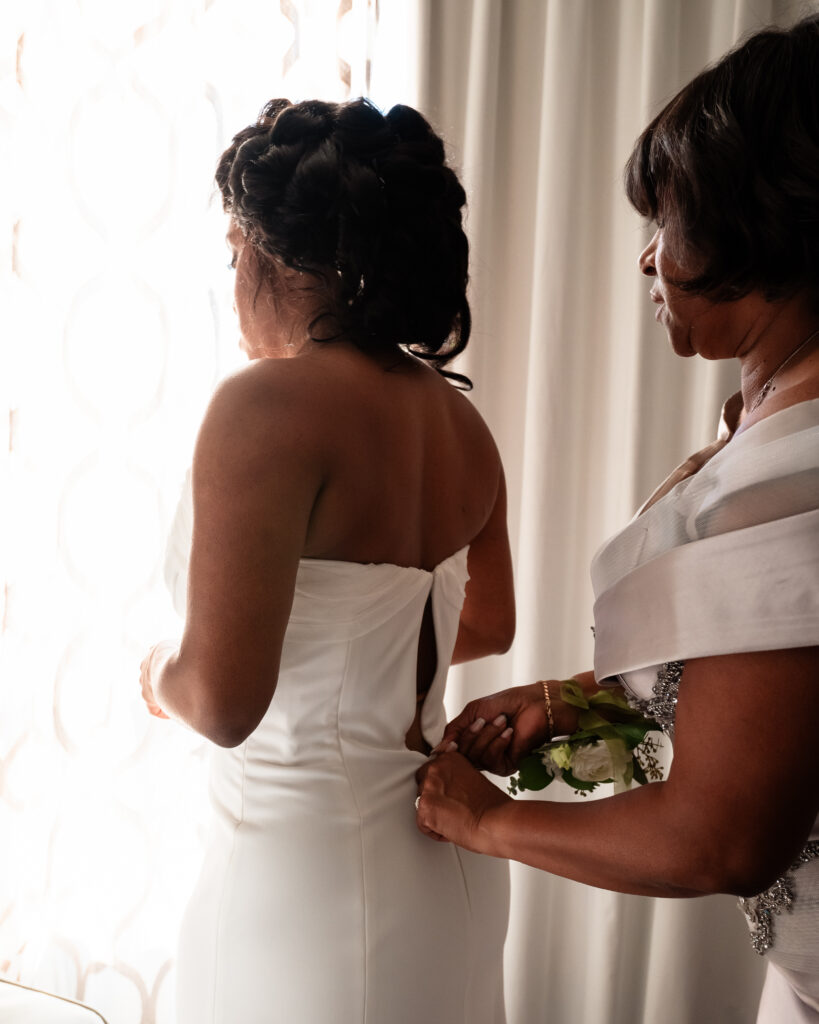 Bride Savonia wearing a Sarah Seven gown with mom buttoning it up