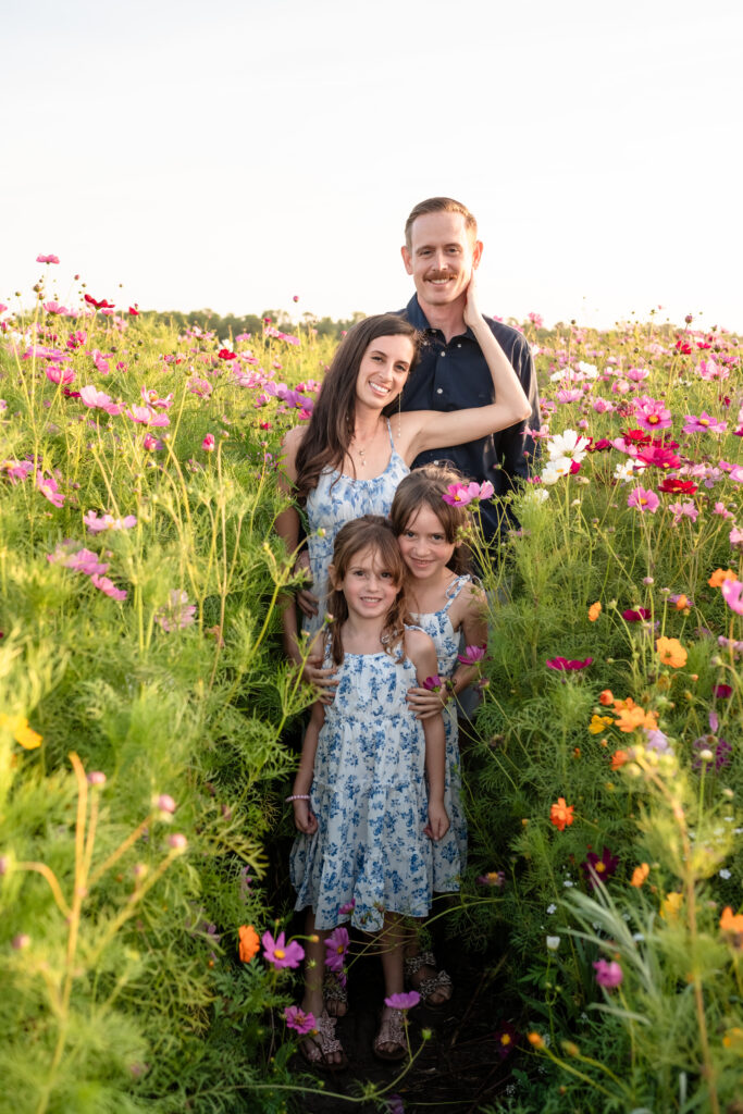 family smiling together in a wildflower field during spring mini sessions in jacksonville florida