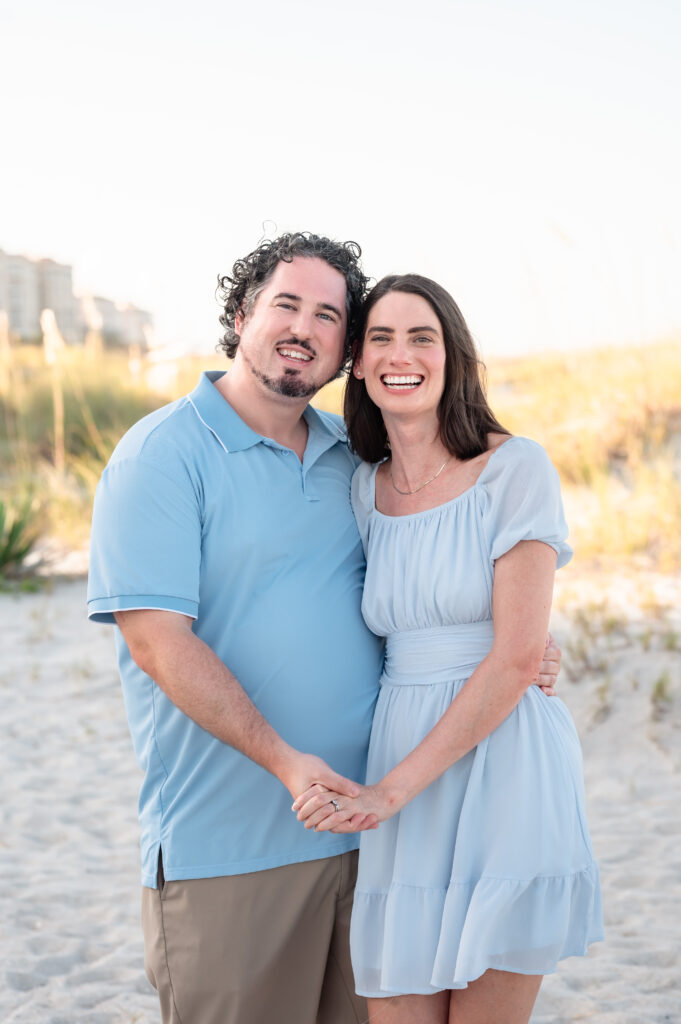 Couple smiling in the dunes at Omni Amelia Island Resort during sunset.