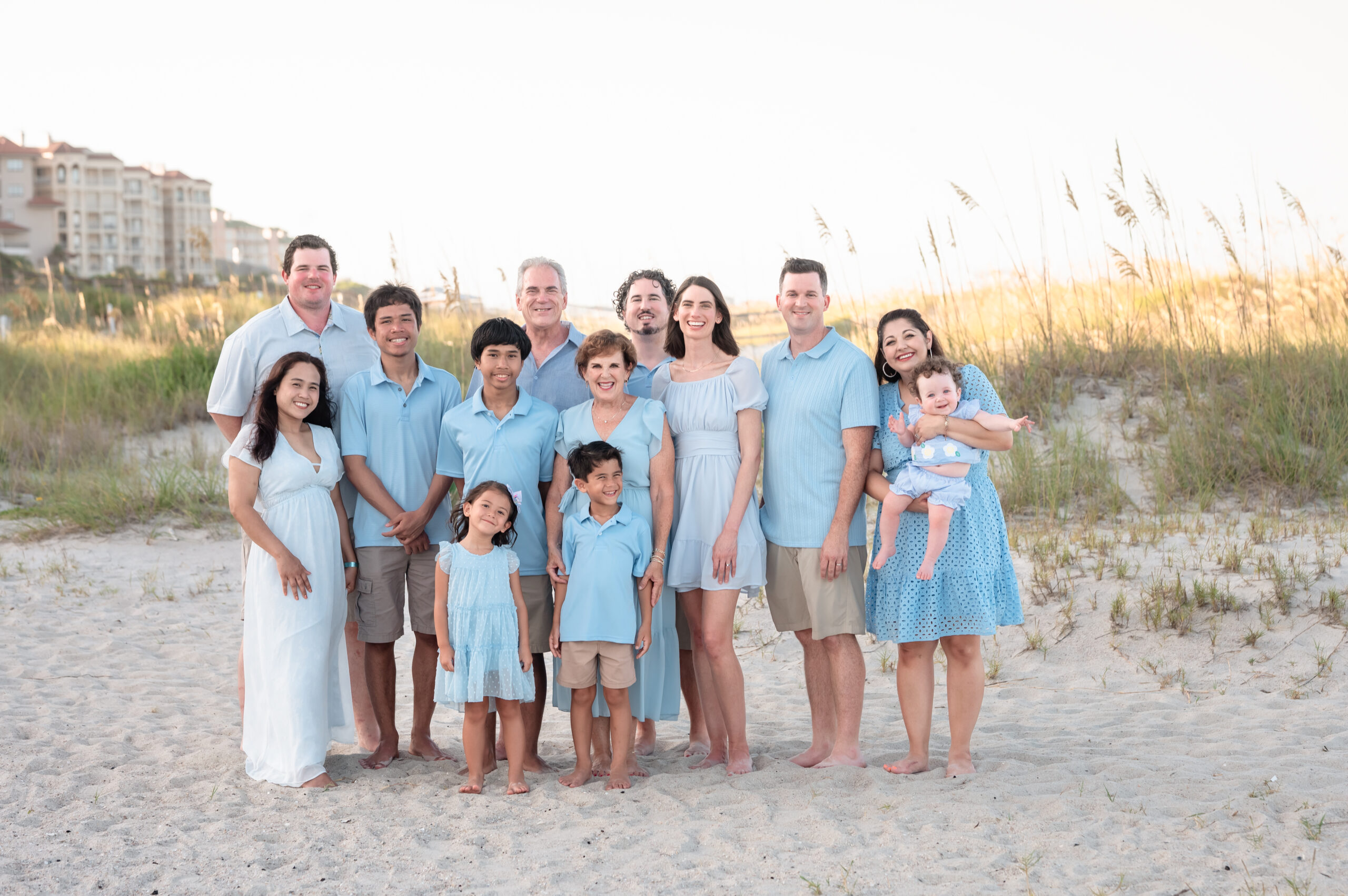 Three generations of the Denning family in coordinated blue outfits smiling in the sand dunes at Omni Amelia Island Resort.