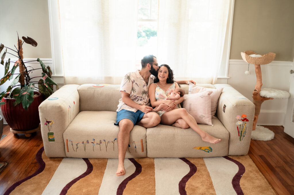 mother cradling newborn daughter on living room couch at home