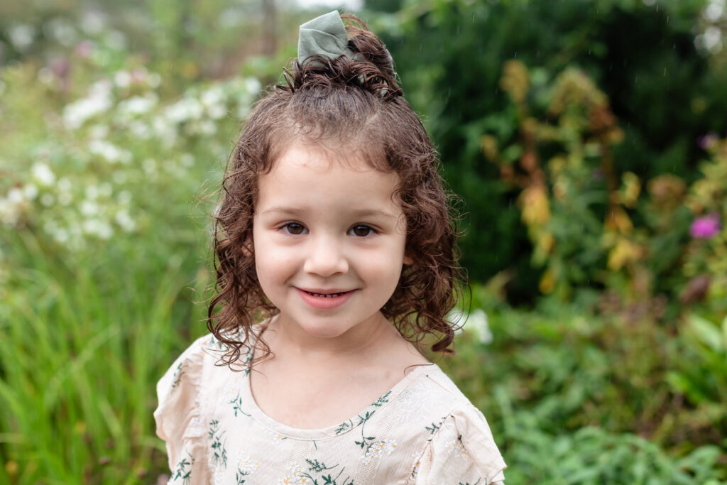 Toddler girl smiling next to flowers in Fredericksburg