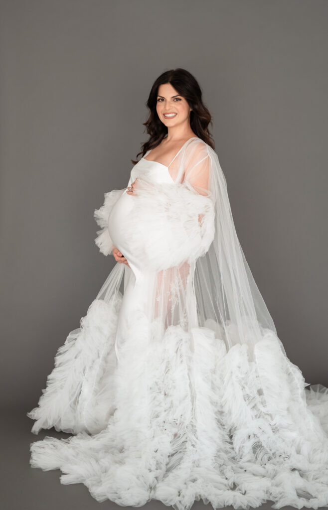 Close-up of baby bump with tulle robe during a studio maternity session.