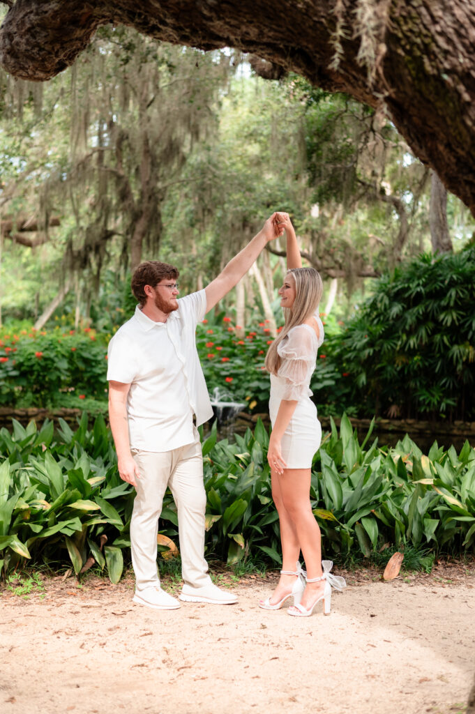 Kristen and Brandon twirling under oak trees with Spanish moss.