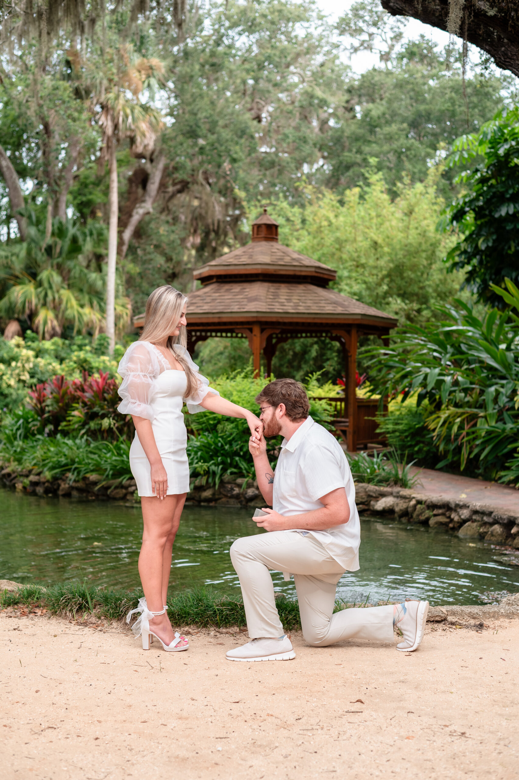 Brandon kneeling while proposing to Kristen at Washington Oaks Gardens State Park.