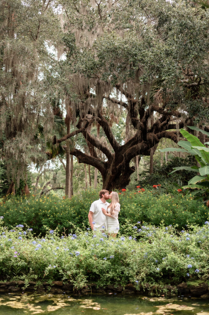 Wide shot of couple surrounded by lush green gardens.