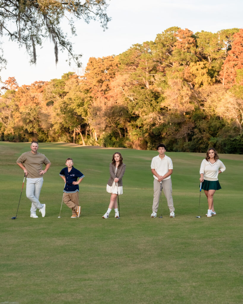 Family lined up across the fairway holding golf clubs during Jacksonville golf course photo session