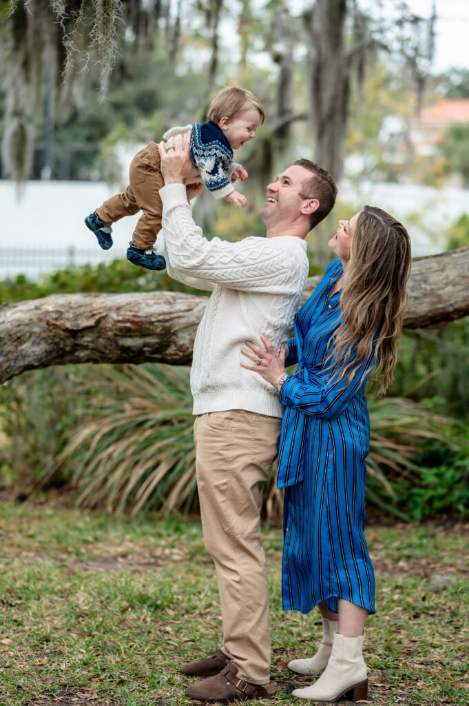 Maternity session at Yacht Basin Park with expecting couple standing by the stone railing overlooking the water in soft natural light.