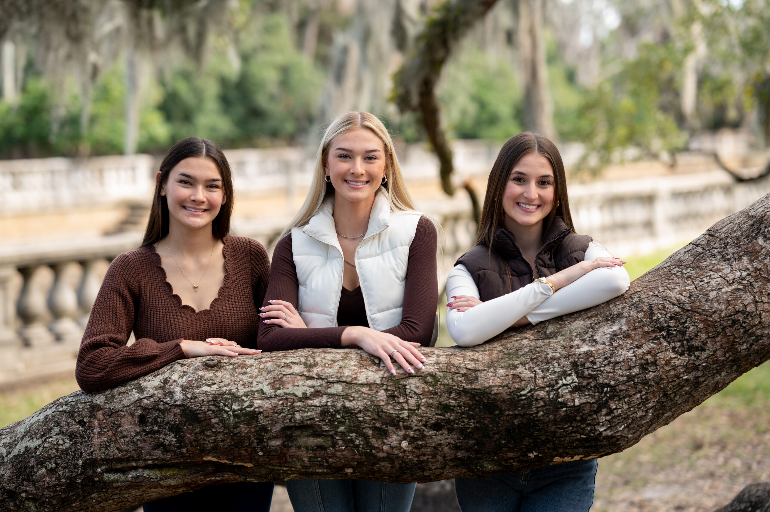 Friends laughing beneath Spanish moss trees during outdoor portrait session