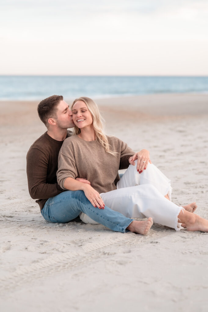 Rachel and Chase sitting together on the beach after their surprise proposal.