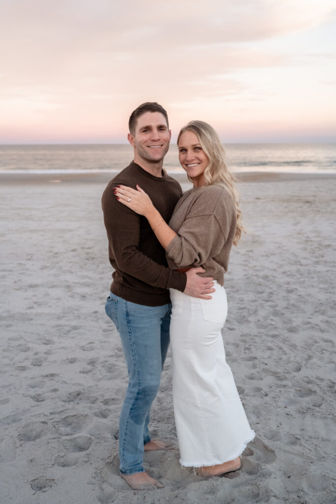 Rachel and Chase smiling together during sunset engagement portraits at Jacksonville Beach.